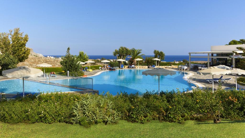 a large swimming pool with umbrellas in a resort at Ville Di Lindos in Lindos