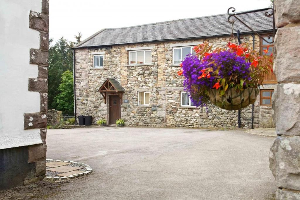 a stone house with a hanging basket of flowers at Cragside Cottage in Troutbeck