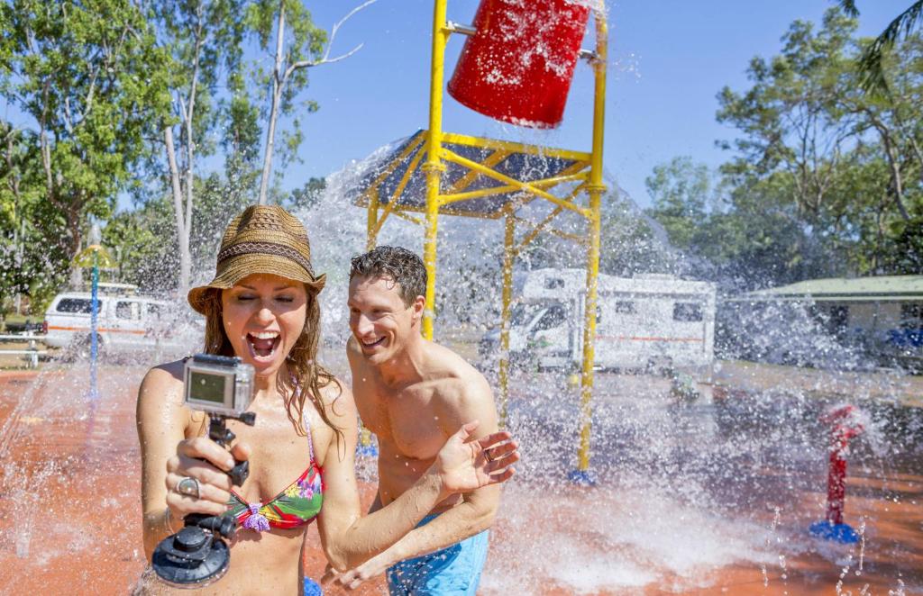 Un uomo e una donna che fanno una foto in una fontana di BIG4 Howard Springs Holiday Park a Darwin