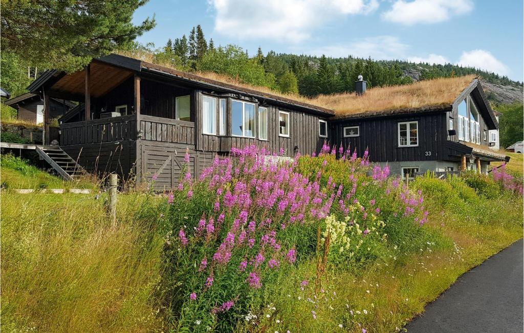 a house with a grass roof and a field of flowers at Cozy Home In Rysstad With House Sea View in Rysstad