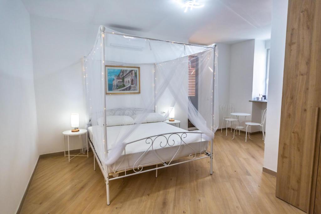 1 dormitorio con 1 cama con dosel y 2 mesas en Around Lago Maggiore rooms, en Reno Di Leggiuno