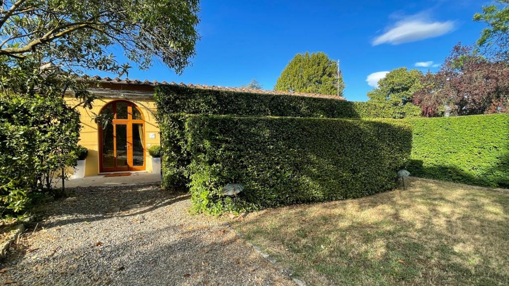 a building covered in green ivy next to a yard at la limonaia in Florence