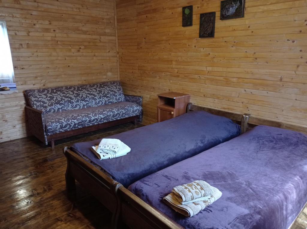 a room with two beds and a bench in a cabin at Садиба над потічком in Oriv