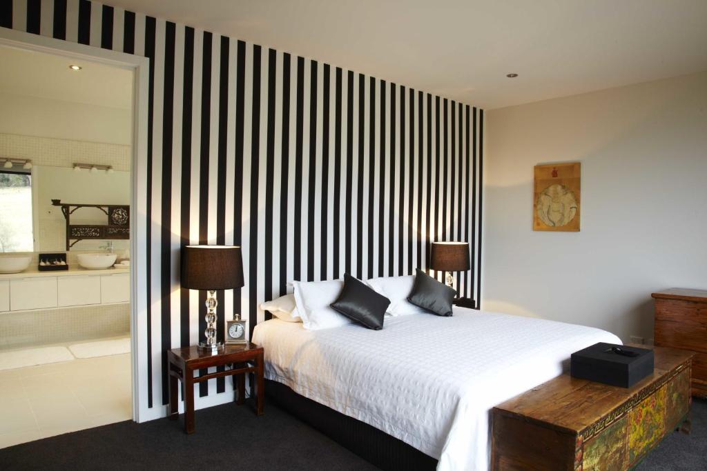 a bedroom with a large bed with a black and white striped wall at Dragonfly Lodge in Swansea