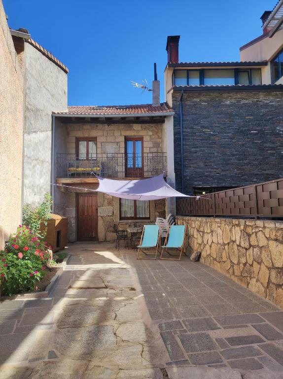 a patio with two chairs and an umbrella in front of a building at CASA RURAL EL TOLEO in Hoyos del Espino
