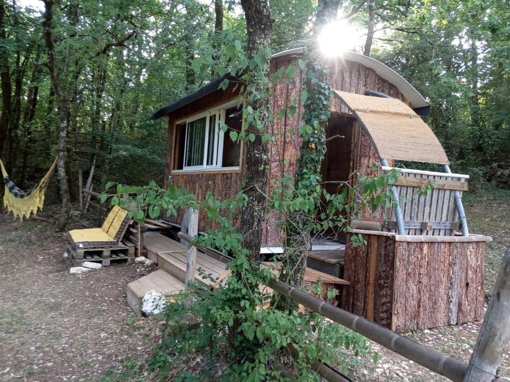 eine Hütte im Wald mit einer Veranda und einer Bank in der Unterkunft Echappée sauvage in Masquières