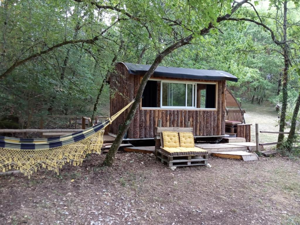 a cabin in the woods with a hammock in front of it at Echappée sauvage in Masquières