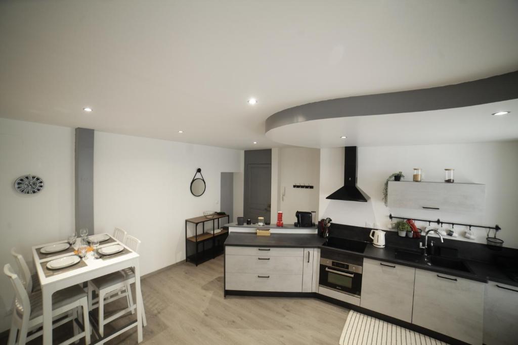 a large kitchen with white cabinets and a counter at Grand Appartement 2 chambres avec Fibre et Netflix in Belfort