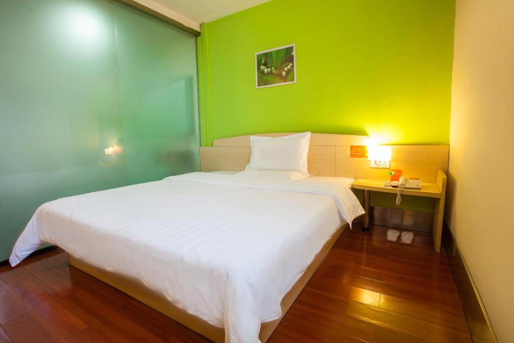 a bedroom with a white bed and a green wall at 7Days Inn Zhuhai North Railway Station Jinding in Zhuhai