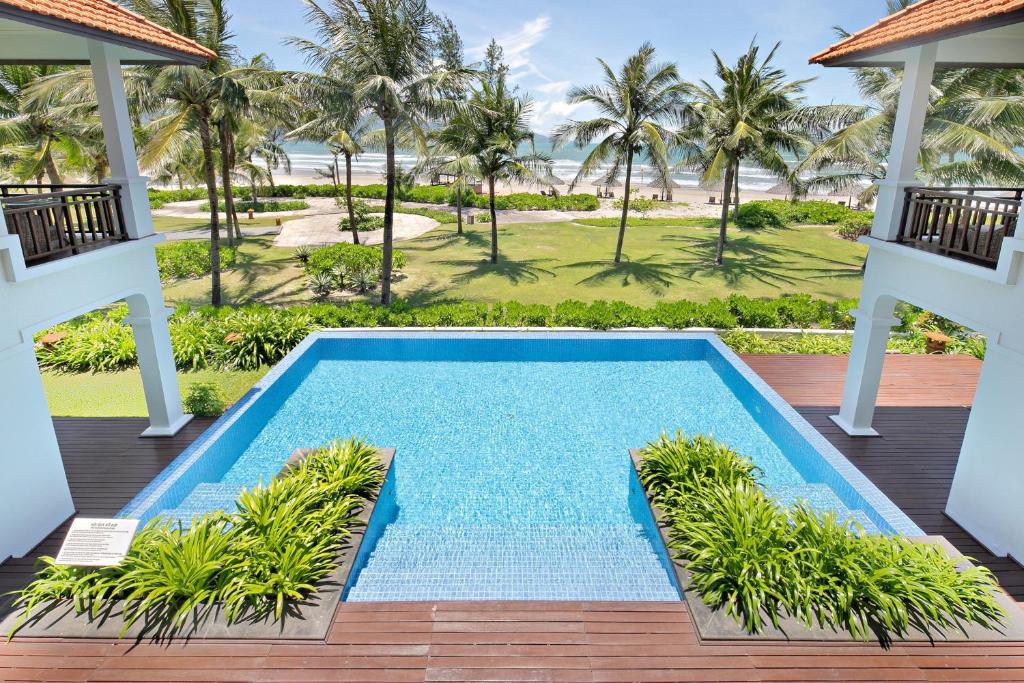 uma piscina de beiral infinito no deque de um resort com palmeiras em Da Nang Paradise Center My Khe Beach Resort & Spa em Da Nang