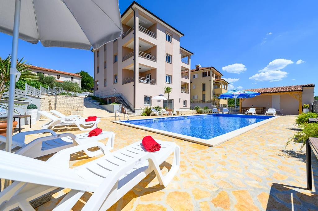 eine Villa mit einem Pool und Liegestühlen in der Unterkunft Stancija Amorozo 5 in Poreč
