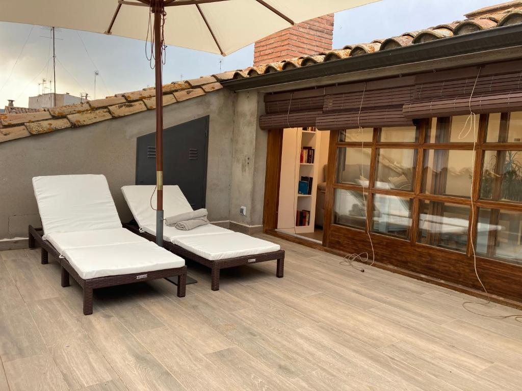 eine Terrasse mit 2 Stühlen und einem Sonnenschirm in der Unterkunft Apartamento céntrico con WIFI y climatizado de 1 habitación y sofá-cama para 3 personas in Santa Coloma de Farners