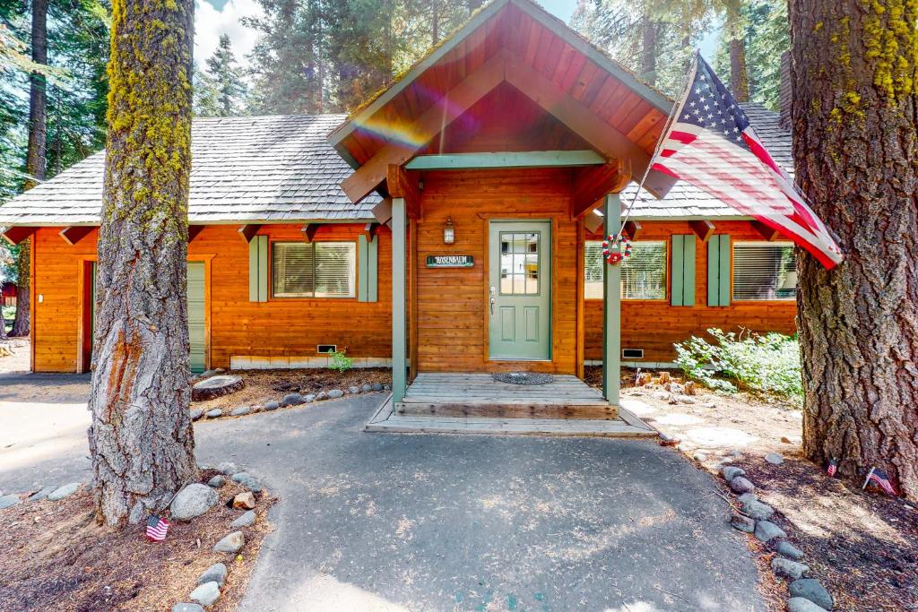 a log cabin with an american flag in front of it at Tahoe Pines Cabin in Homewood