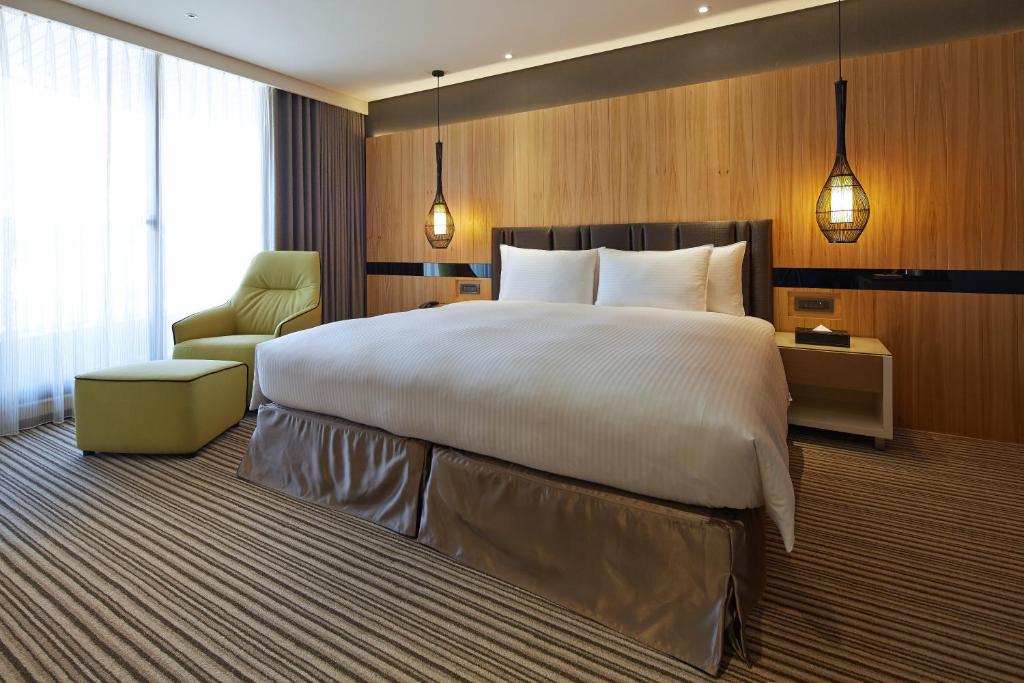a hotel room with a large bed and a chair at La Vida Hotel in Taichung