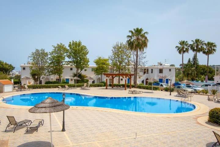 a large swimming pool with chairs and an umbrella at STAY Symphony Apartment in Protaras