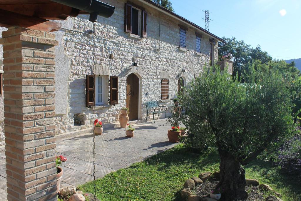 een stenen huis met een binnenplaats ervoor bij B&B Il Poggetto in Serra SantʼAbbondio