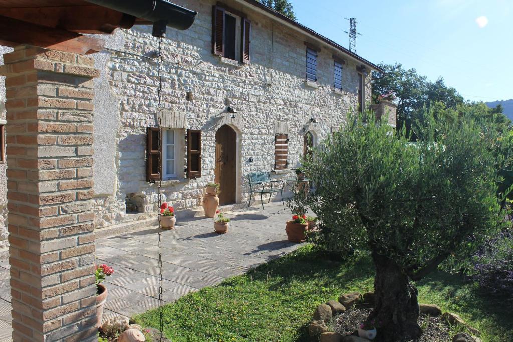 una casa de piedra con un patio frente a ella en B&B Il Poggetto, en Serra SantʼAbbondio