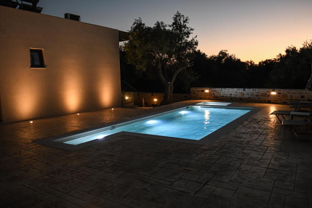 a swimming pool with lights in a backyard at night at PAUL'S VILLA PLAKIAS in Plakias