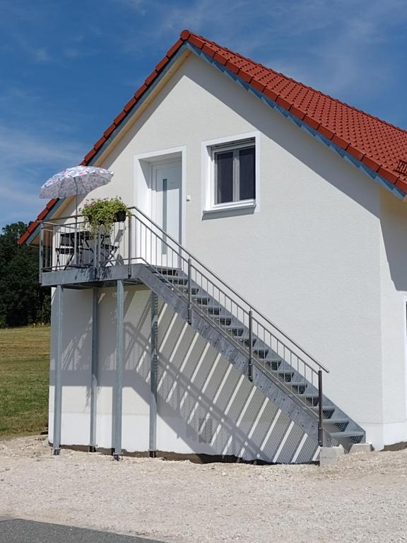 a white house with a staircase and an umbrella at Ferienwohnung Regina in Berching