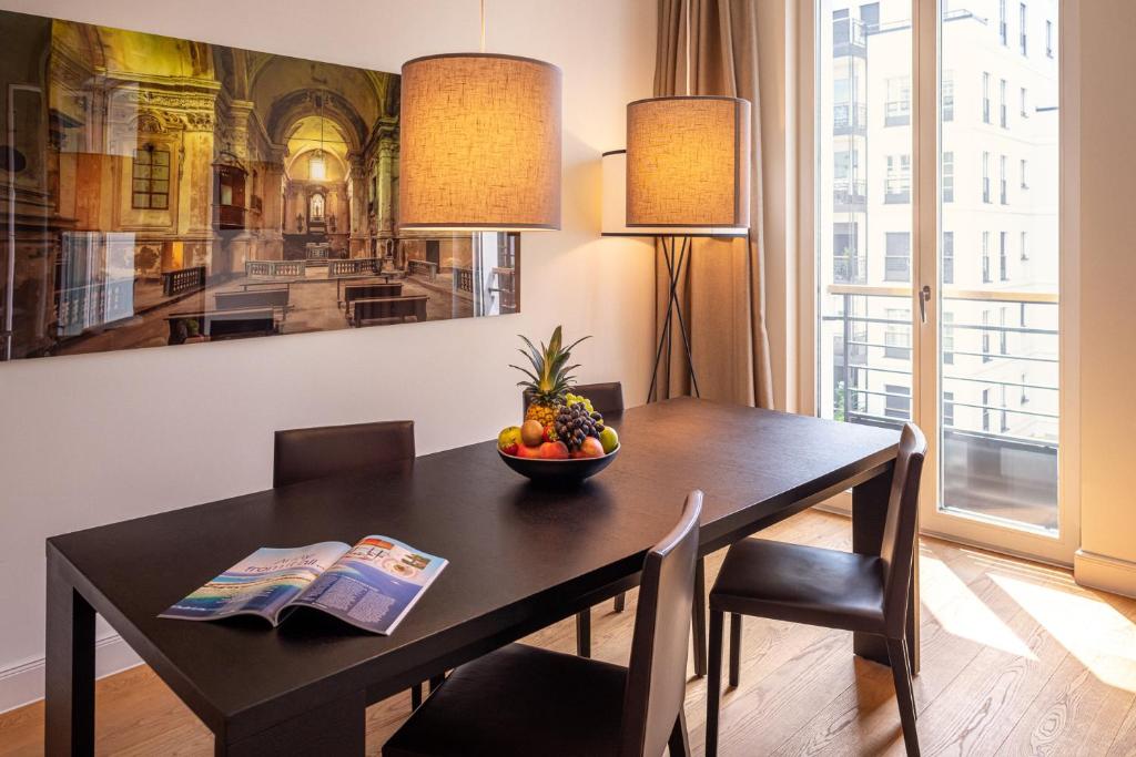 a dining room table with a bowl of fruit on it at The Wellem Residences in Düsseldorf