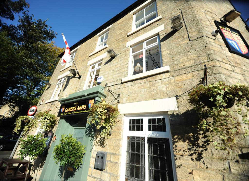 a brick building with a white door and windows at Queens arms country inn in Glossop