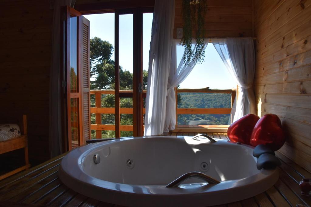 uma grande banheira num quarto com uma janela em Pousada Recanto Vale da Serra Chales em São Francisco de Paula