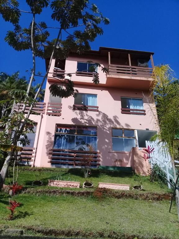 un bâtiment rose avec des arbres devant lui dans l'établissement La Casa Rozada Prumirim, à Ubatuba