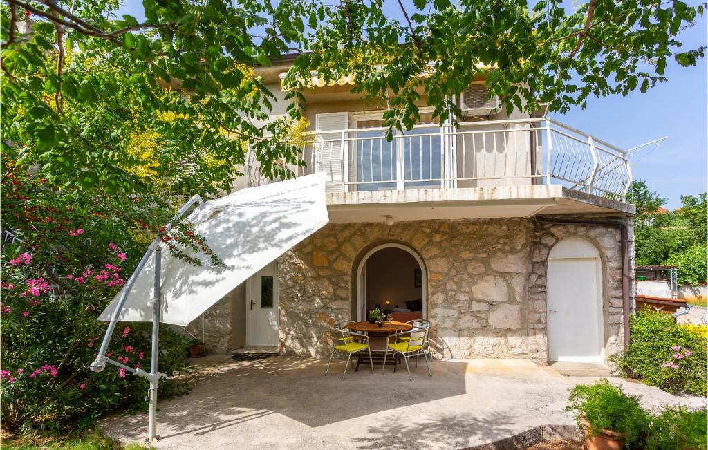 ein Haus mit einem Balkon und einem Tisch davor in der Unterkunft Awesome Apartment In Omisalj With Wifi in Omišalj