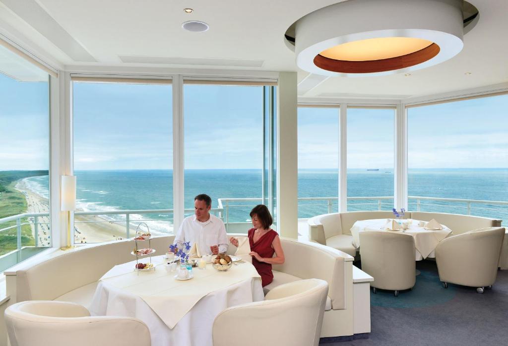 a man and a woman sitting at tables in a restaurant at Hotel Neptun in Warnemünde