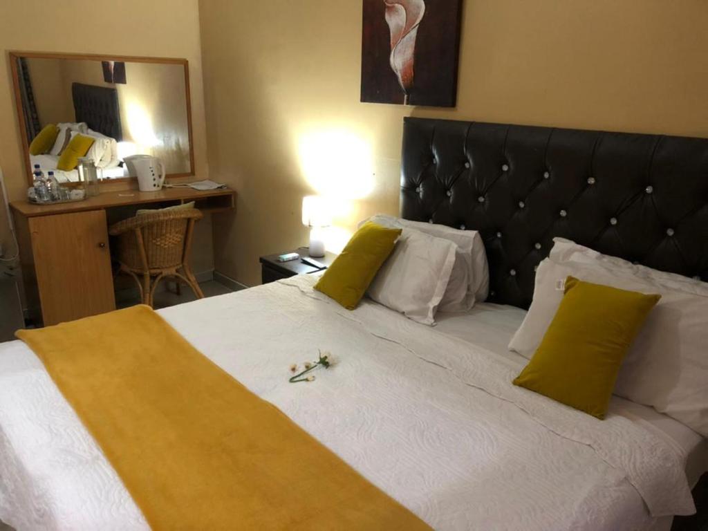ein Schlafzimmer mit einem großen Bett mit gelben und weißen Kissen in der Unterkunft Ntshe River Lodge in Francistown