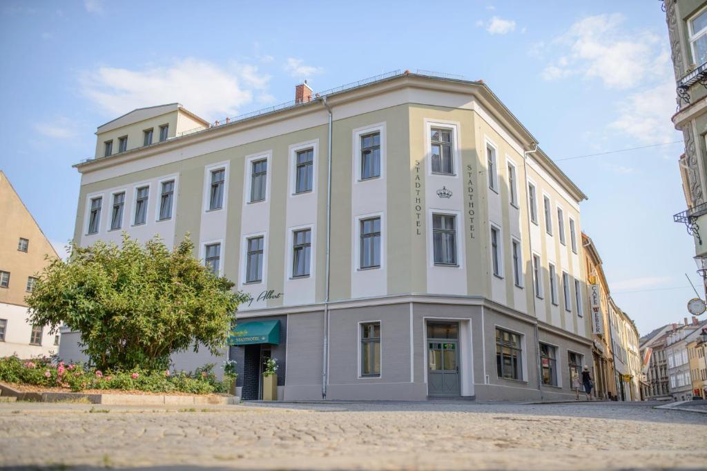 un grand bâtiment blanc au coin d'une rue dans l'établissement Stadthotel König Albert, à Zittau