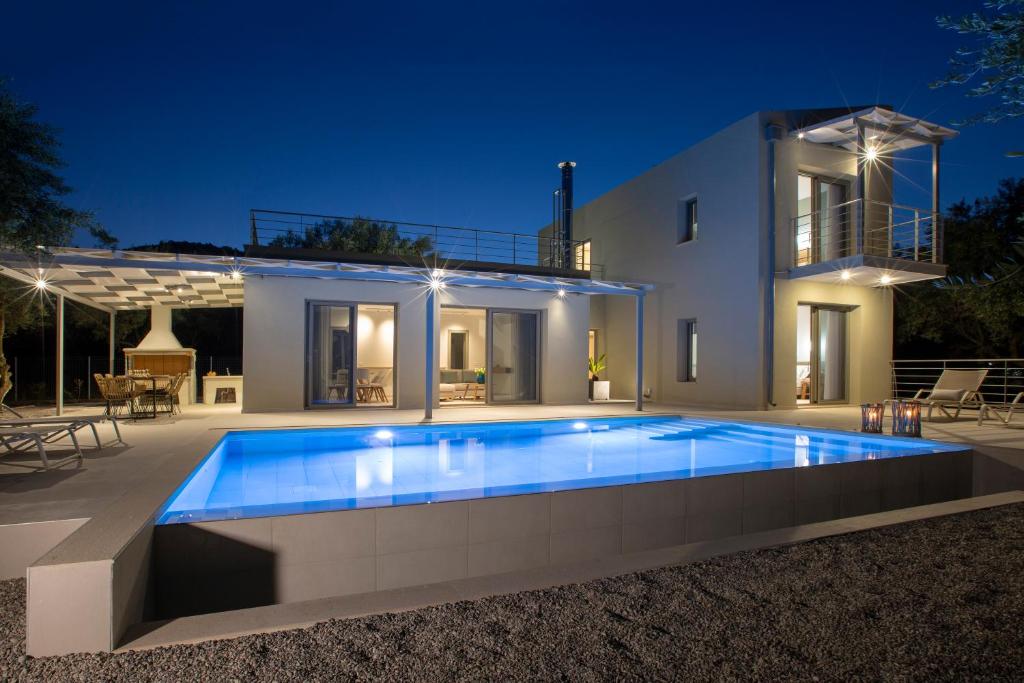 a swimming pool in front of a house at night at villa-agrielia in Nikiana