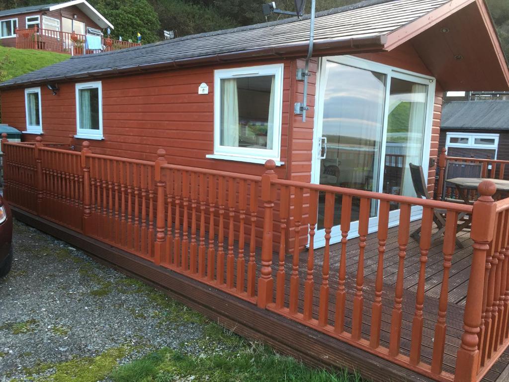 a red cabin with a large deck at Bazanmoes Shed No: 49 in Aberystwyth