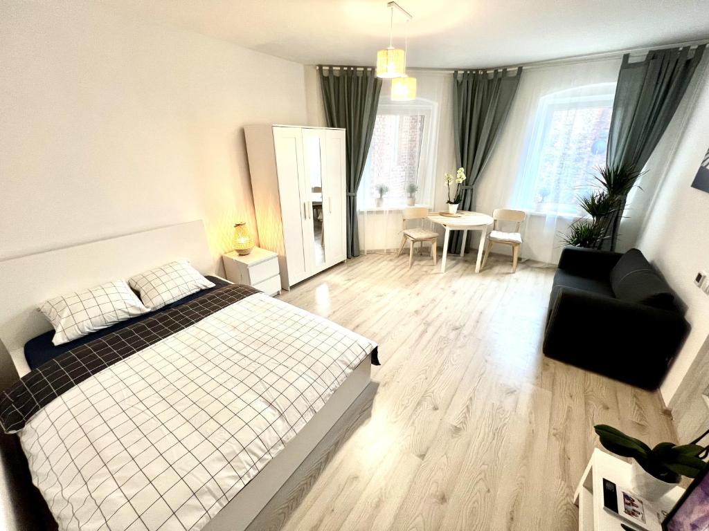 a bedroom with a bed and a chair and a table at New York Apartments in Katowice