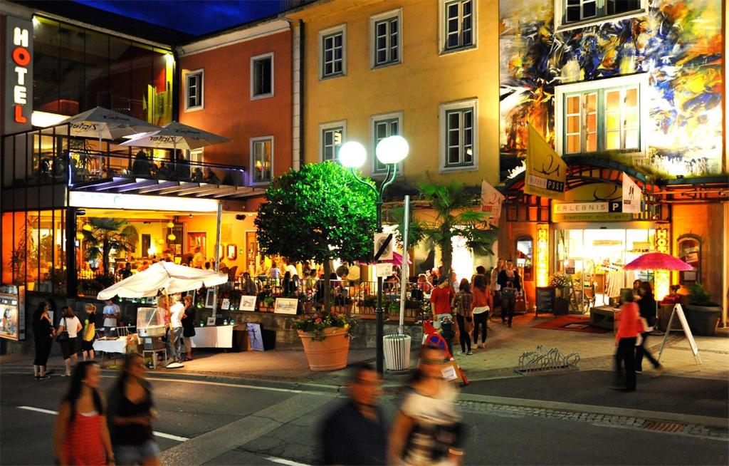 a group of people walking on a city street at night at Erlebnis Post - Stadthotel mit EigenART in Spittal an der Drau