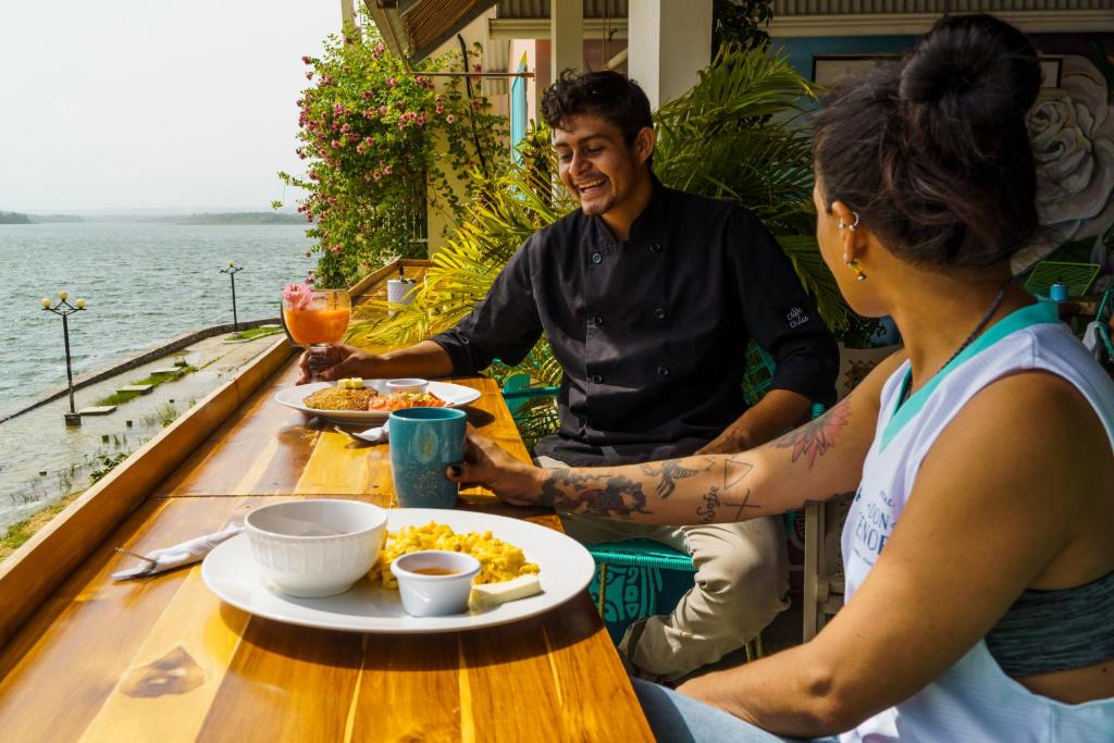 Ein Mann und eine Frau sitzen am Tisch und essen Essen. in der Unterkunft Hostal Don Cenobio in Flores