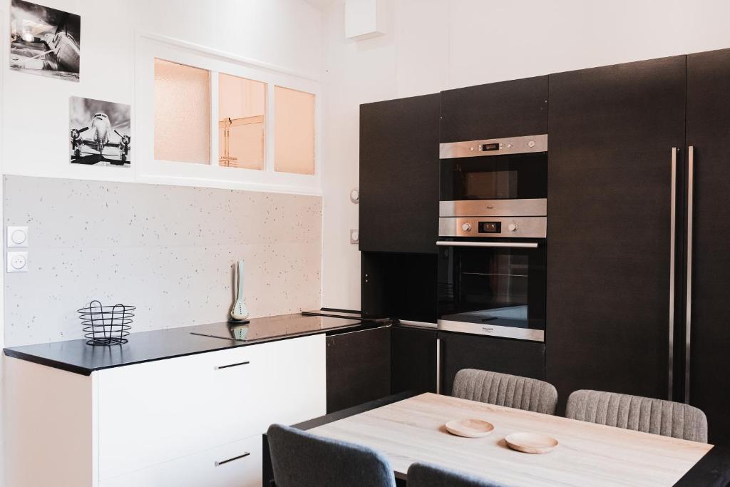 a kitchen with black and white cabinets and a table at R&#39;Apparts T2 Au Grenoblois Dormant in Grenoble