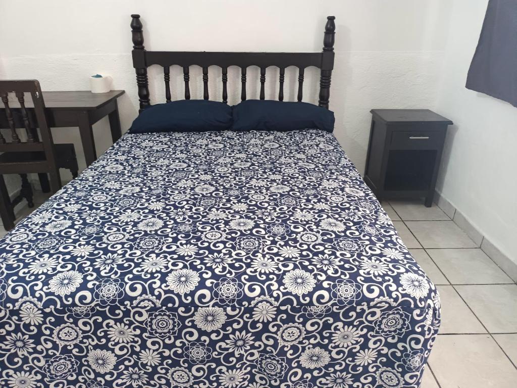a bed with a blue and white comforter on it at Hotel Kiko in Mazatl&aacute;n