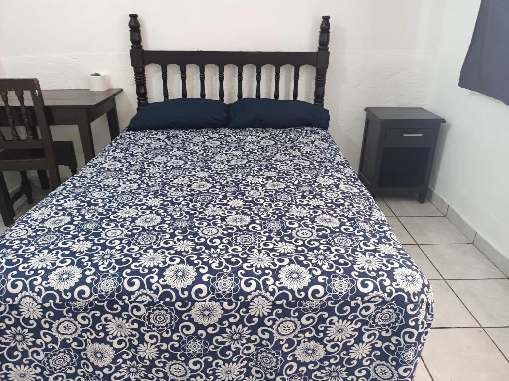 a bed with a blue and white comforter on it at Hotel Kiko in Mazatlán