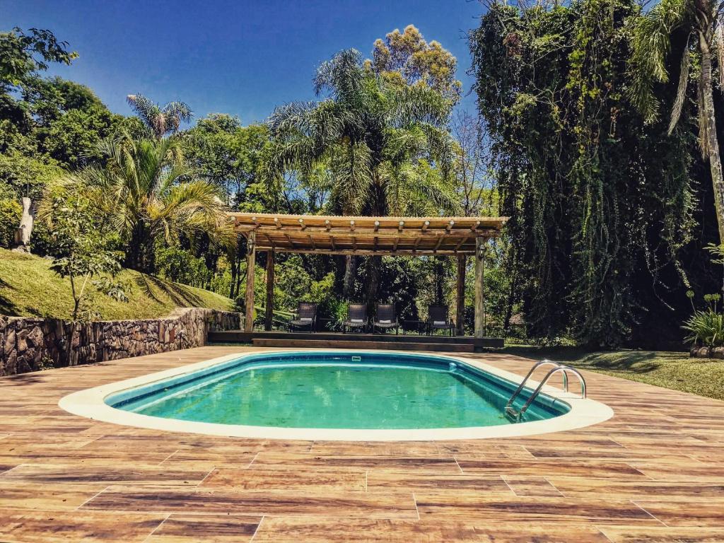 an outdoor pool with a pergola and a swimming pool at Villa Tuiuty Pousada de Charme in Bento Gonçalves