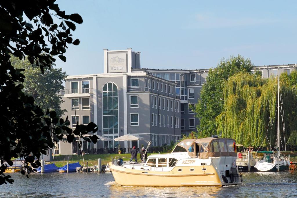 ein Boot im Wasser vor einem Gebäude in der Unterkunft Hotel am Schloß Köpenick by Golden Tulip in Berlin