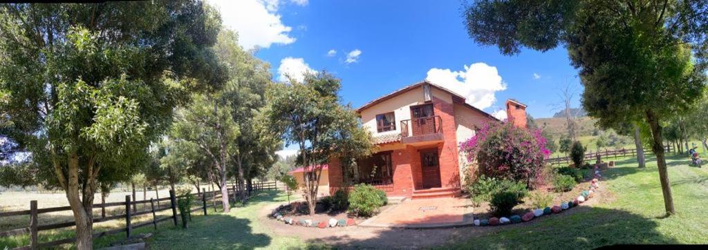 una casa sentada en medio de un campo en BS HOTEL CAMPESTRE, en Cucunubá