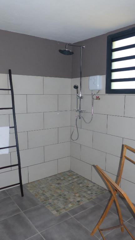 a white tiled bathroom with a shower in a room at Bois de Santal Chambre d&#39;hôtes in Saint-Pierre