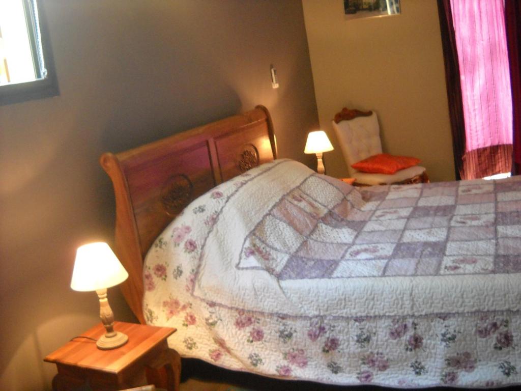 a bedroom with a bed with two lamps and a chair at Bois de Santal Chambre d&#39;hôtes in Saint-Pierre