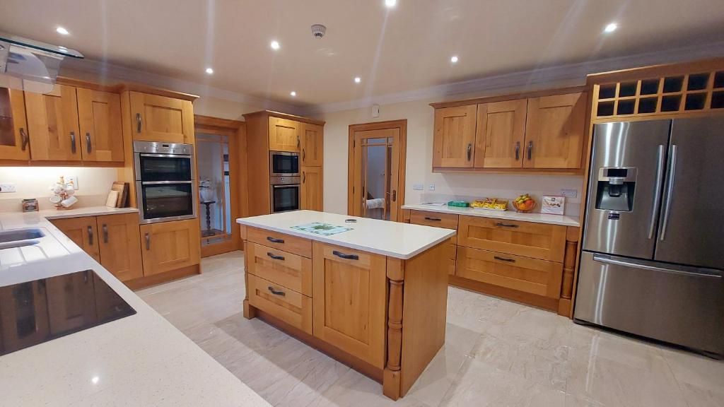 een keuken met houten kasten en een roestvrijstalen koelkast bij Drumsallagh View in Loughbrickland
