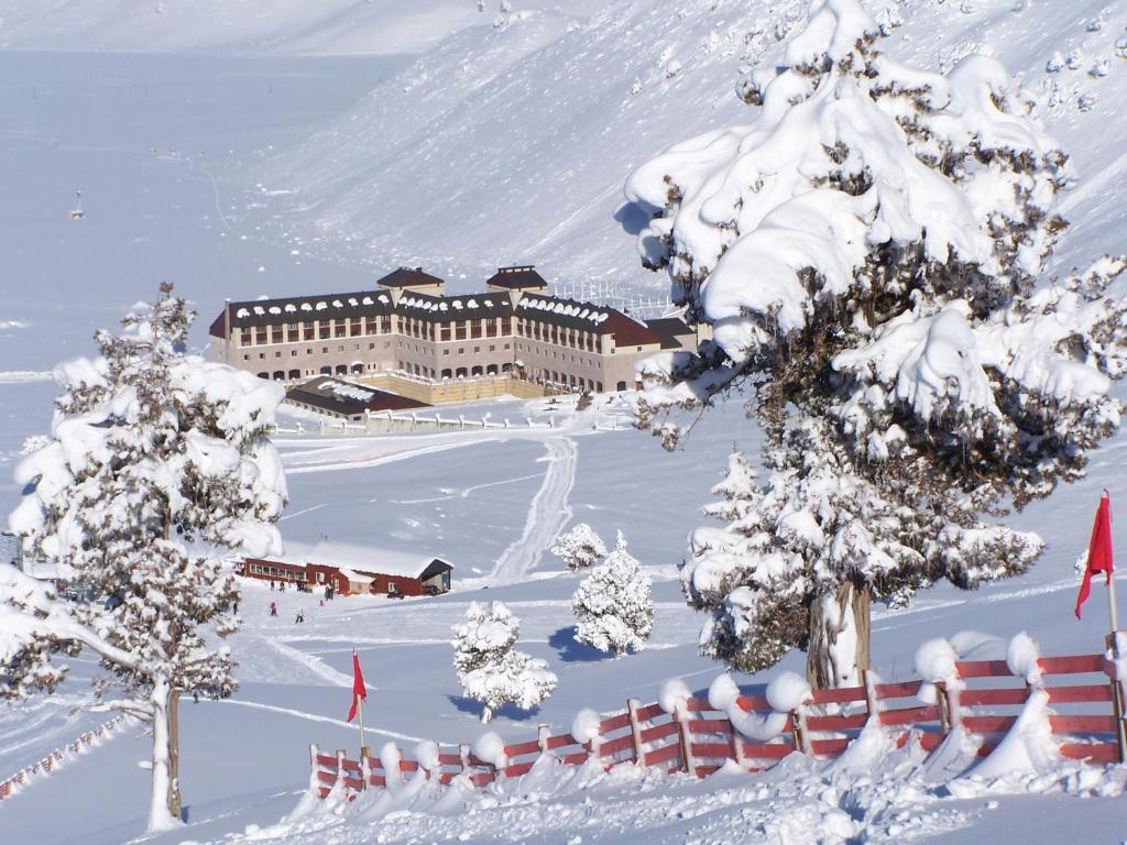 a building covered in snow with trees and a fence at Sirene Davras Hotel in Cobanisa