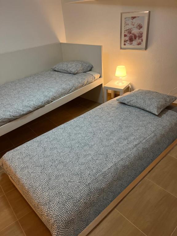 two beds in a bedroom with a lamp on a table at Arte de Marinheiro in Sesimbra