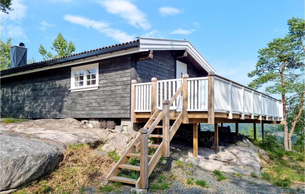 a log cabin with a deck and a staircase at 1 Bedroom Amazing Home In Lyngdal in Lyngdal