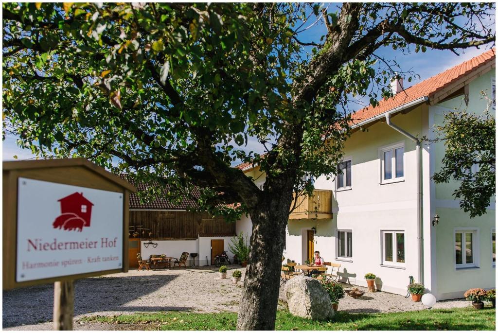 ein Schild vor einem Gebäude mit einem Baum in der Unterkunft Gästehaus Niedermeierhof in Ebersberg