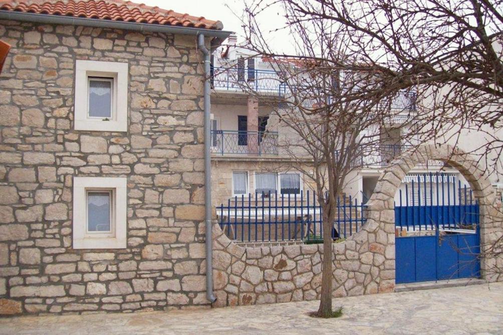 a stone building with a blue door and a tree at Apartment Jezera 5057b in Jezera